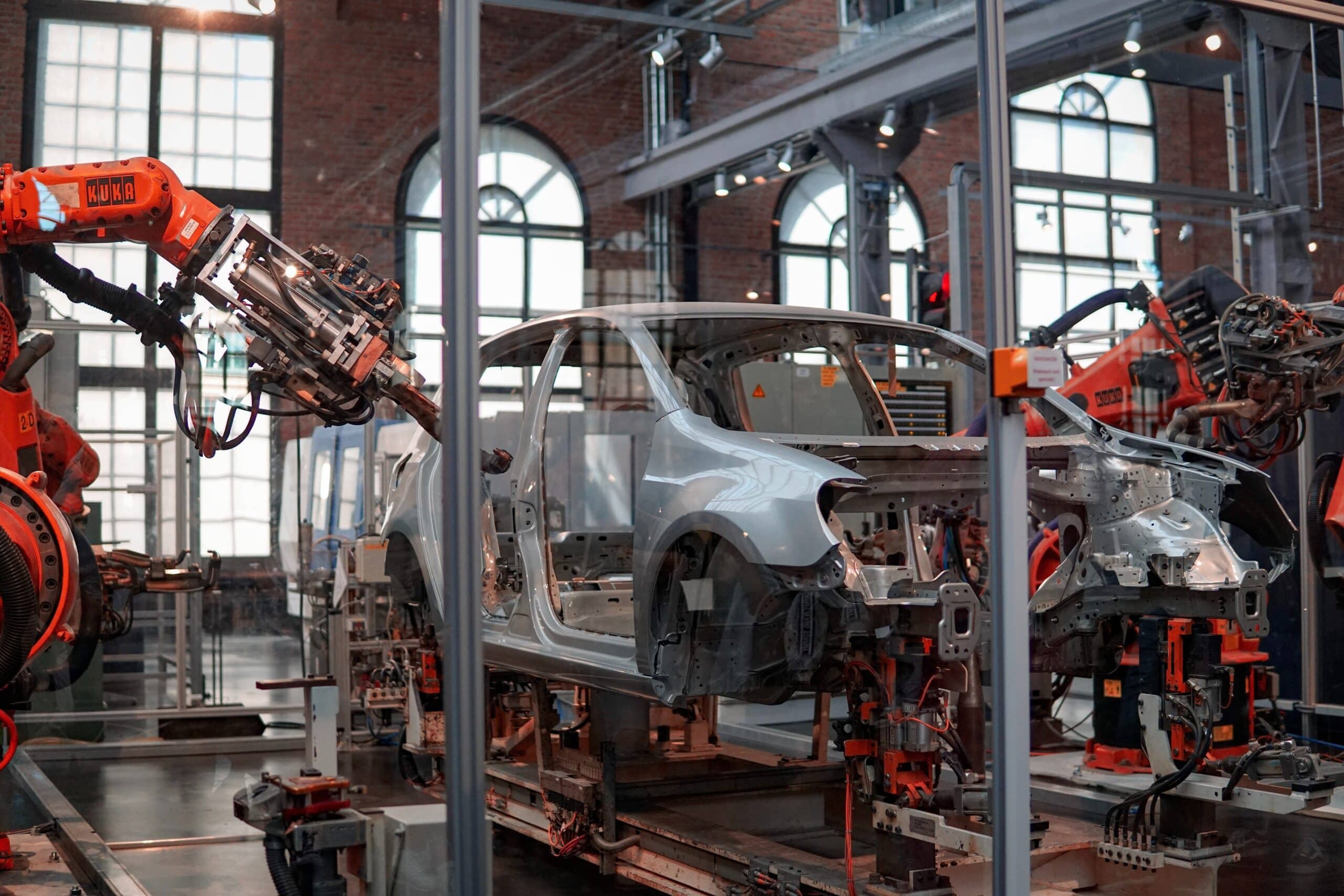 Robotic arms integrated in automotive manufacturing. Steel car frame is being adjusted using robotic arms.